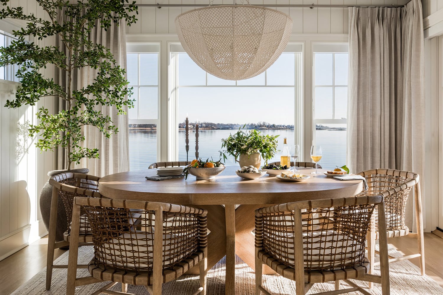 Coastal dining room with white shiplap walls, light oak flooring, and ocean views.