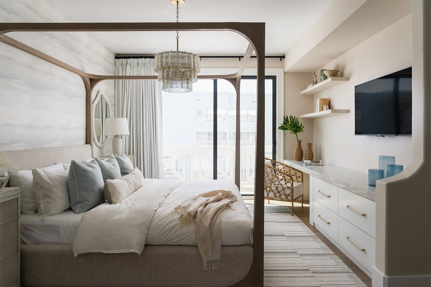 Coastal primary bedroom with warm wood flooring, canopy bed and neutral color scheme.