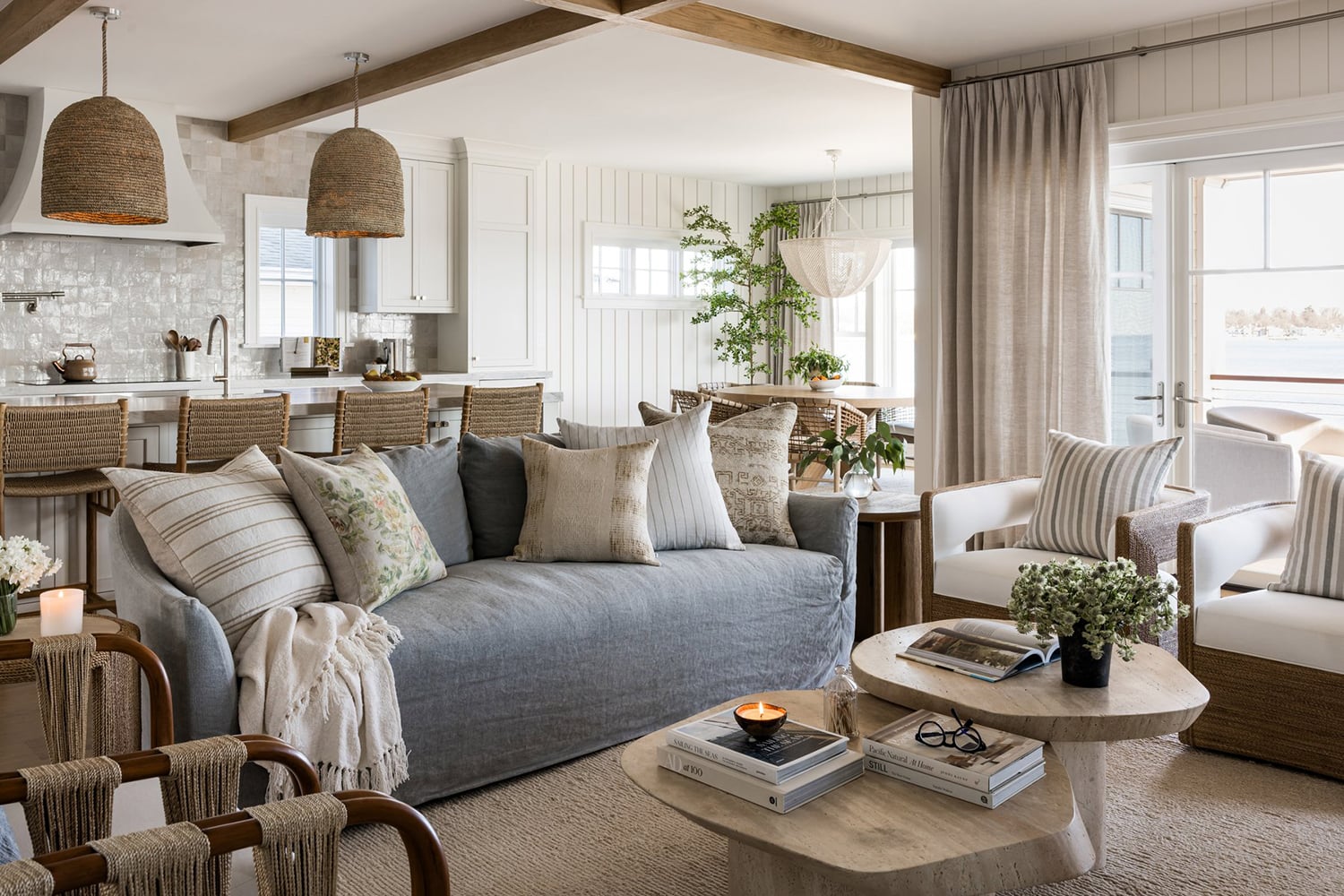 Open-concept coastal living room with white shiplap walls, wood beams and light wood flooring.