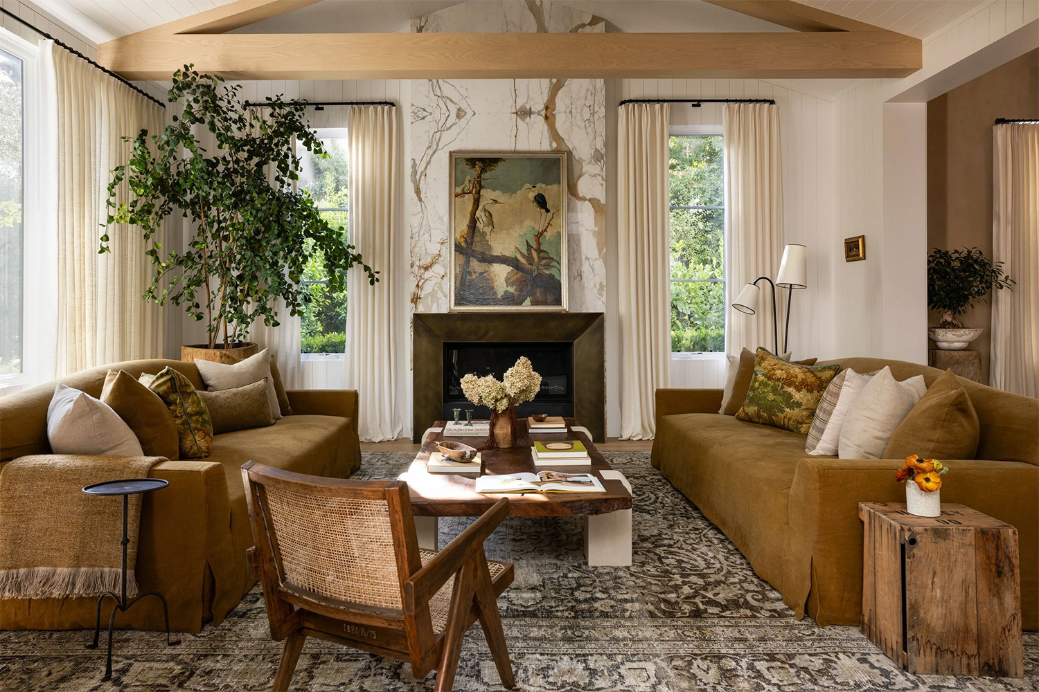 Modern rustic farmhouse living room with golden-toned sofas, green accents and mixed wood tones