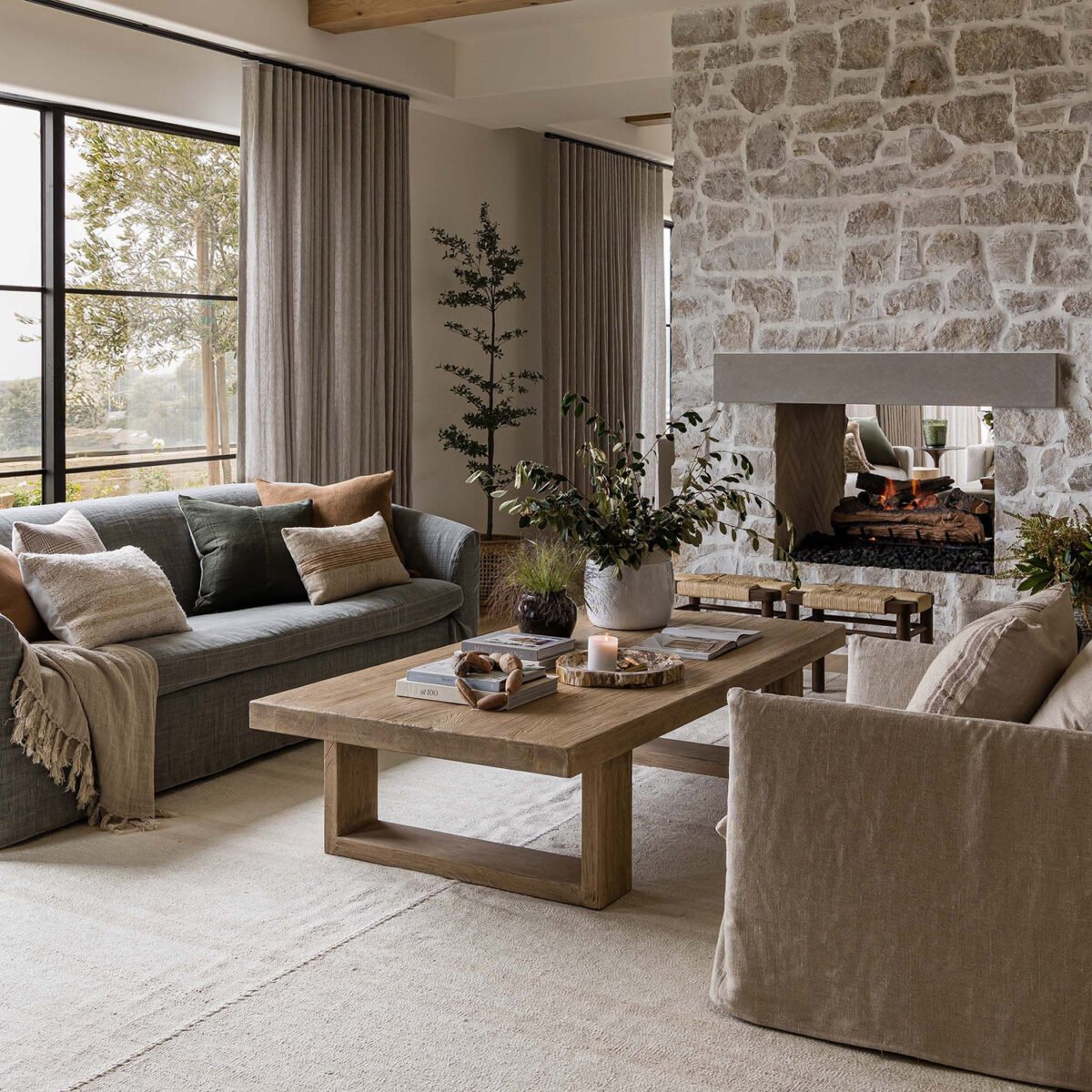 Modern rustic farmhouse living room with a stone fireplace, linen window treatments and a neutral color palette