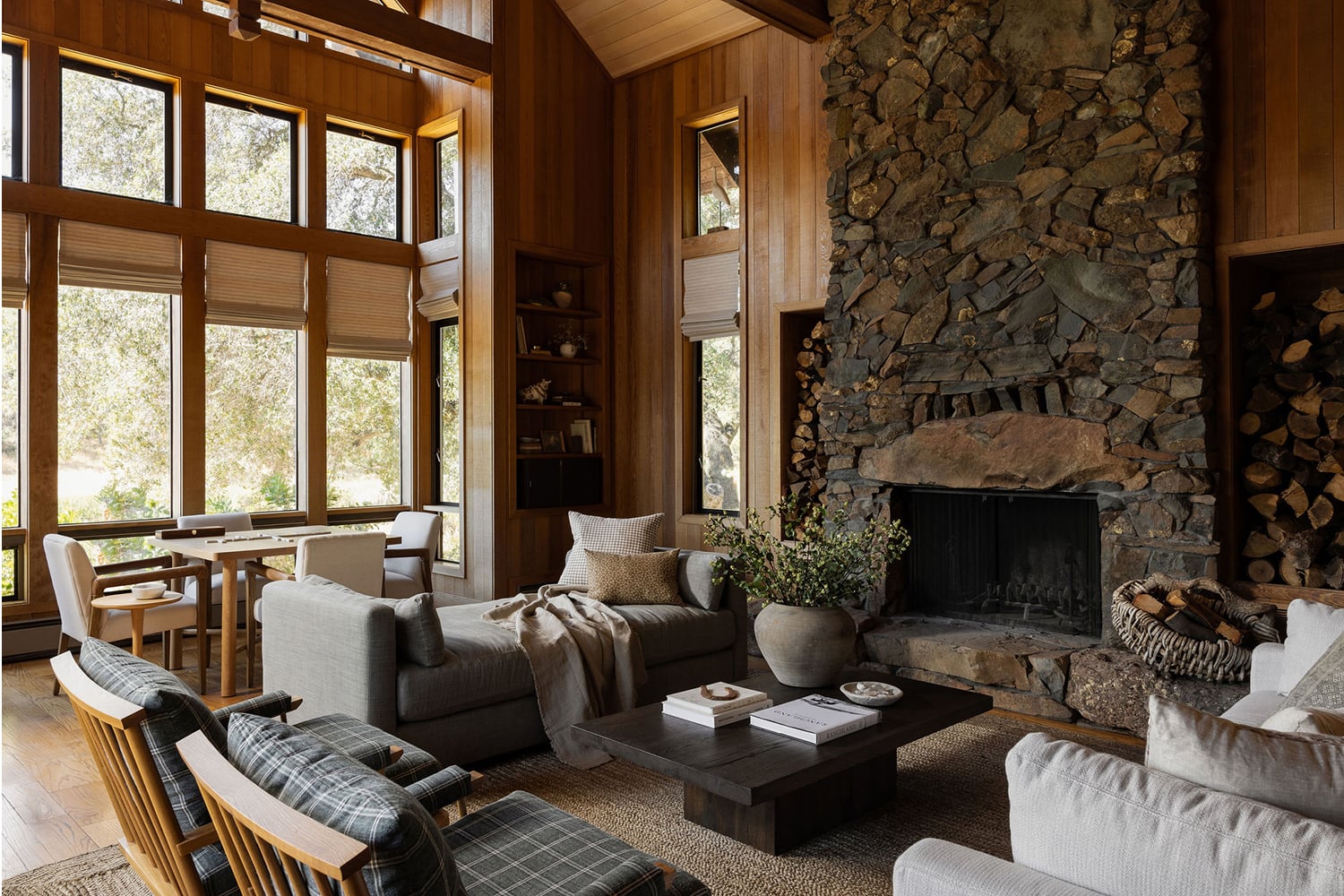 Modern rustic living room with wood-paneled walls and a stone fireplace.
