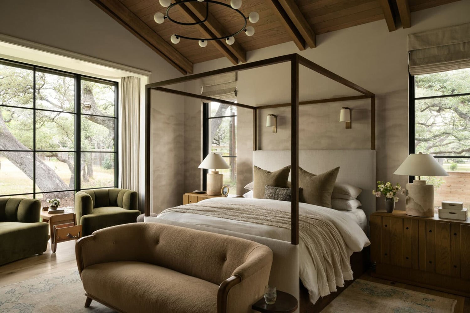 Farmhouse bedroom with dark wood canopy bed, peaked wood ceiling and olive green accent chairs