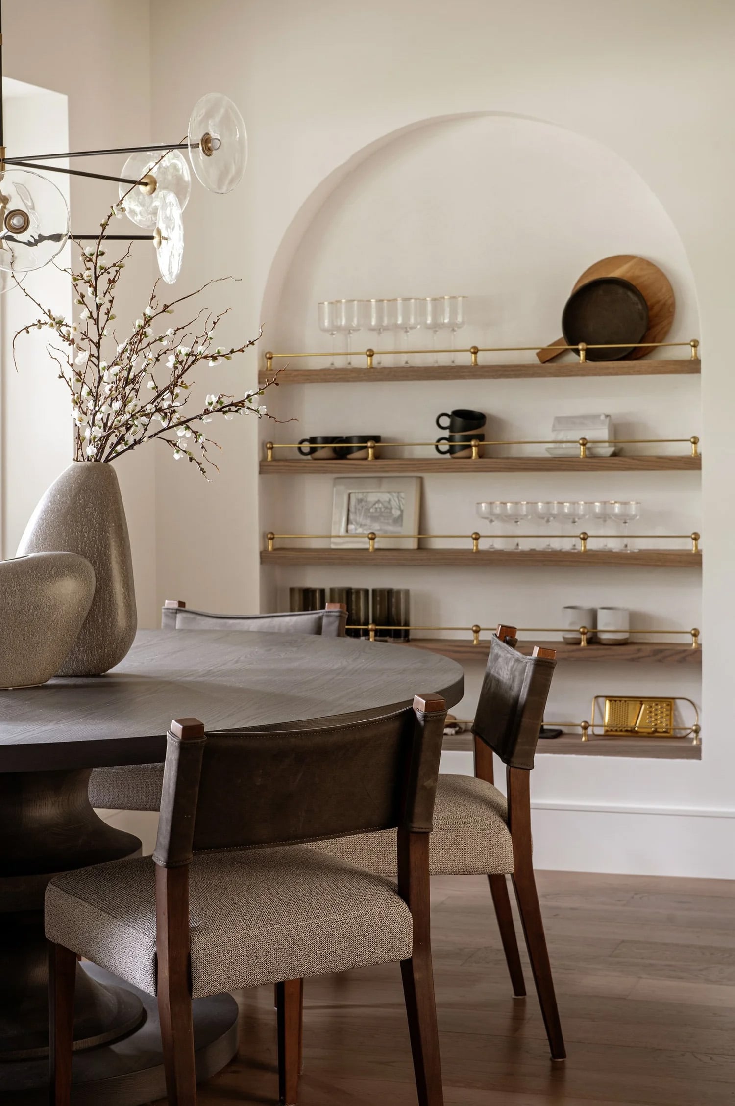 An archway with open wood shelving with brass railing