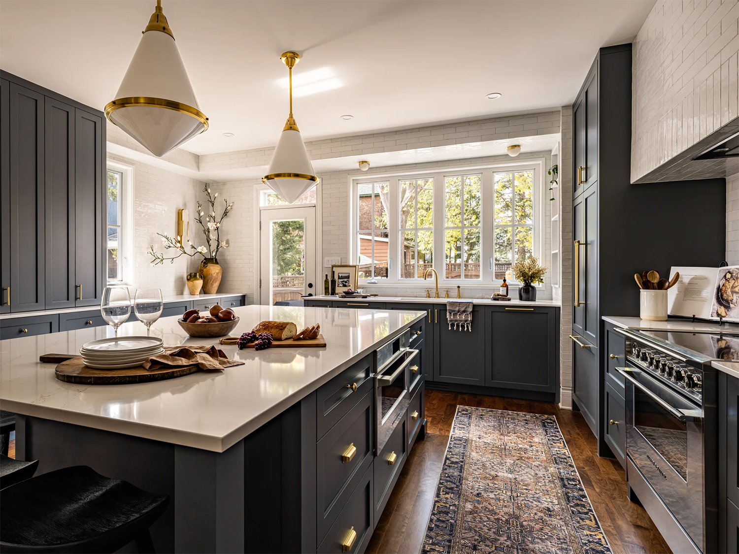Dark blue kitchen cabinets, white subway tile backsplash and dark wood flooring.
