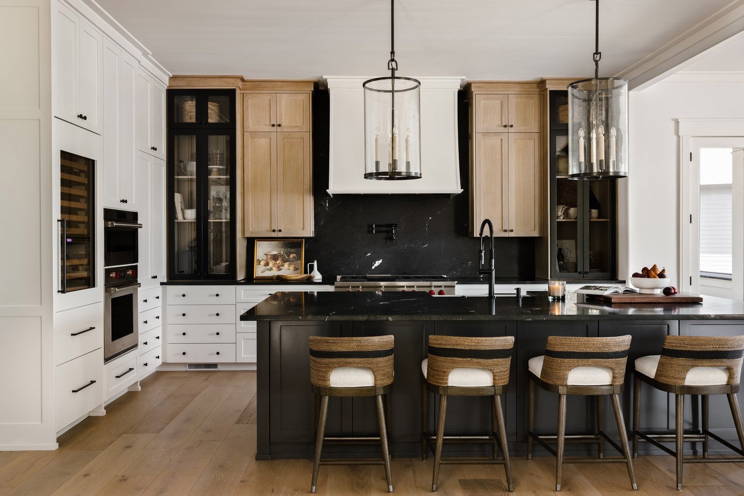 Modern kitchen with combined white and light oak cabinets with black backsplash.