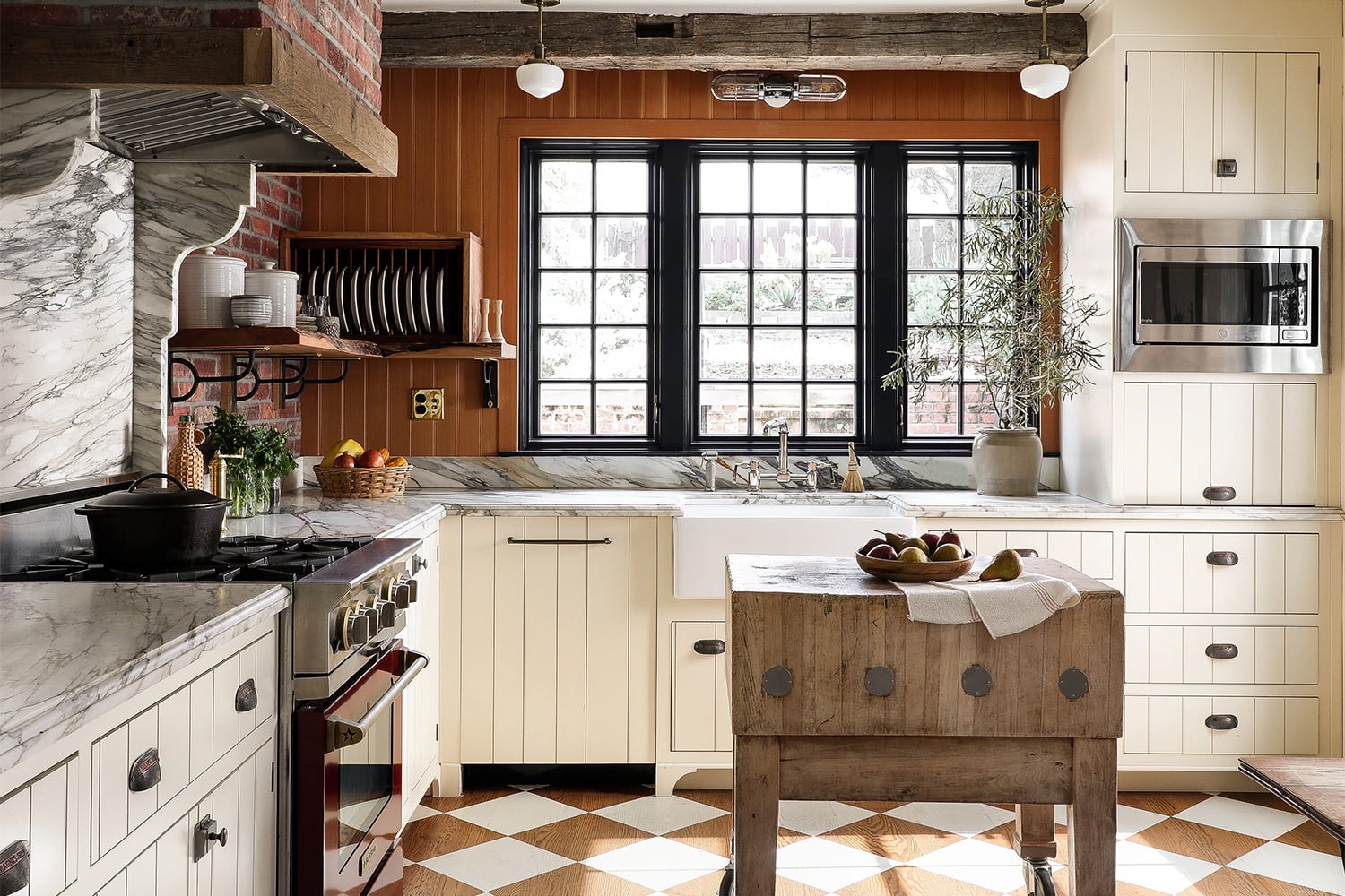 Cream kitchen cabinets in a log home with rustic wood walls amber timber tones and natural wood beams