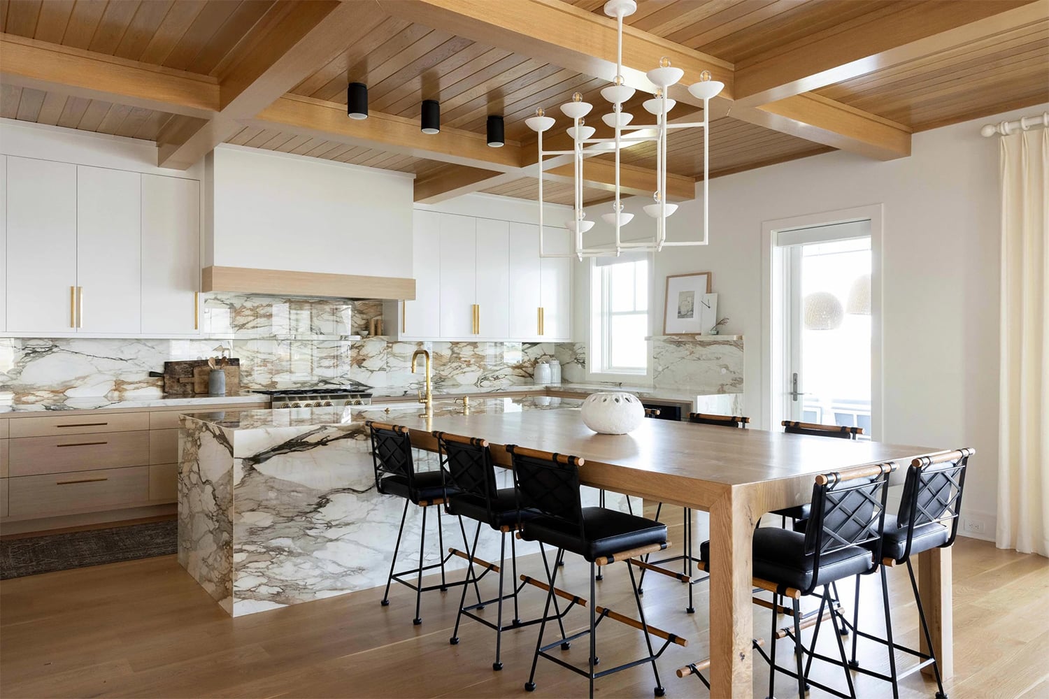 Modern organic kitchen with open shelving, wood island and brass pendant lights.