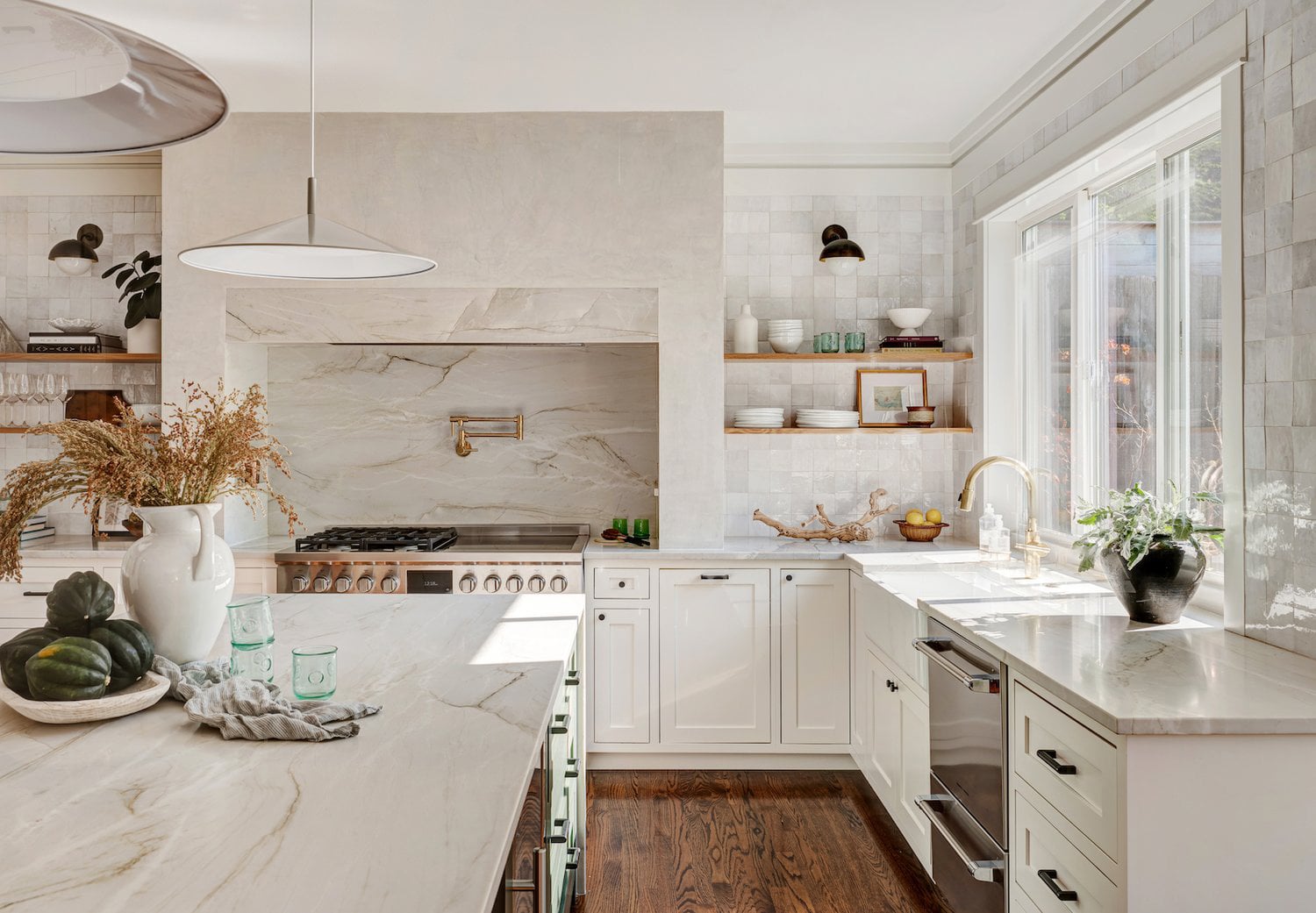 White kitchen with open wood shelving, plants, and fresh greenery.