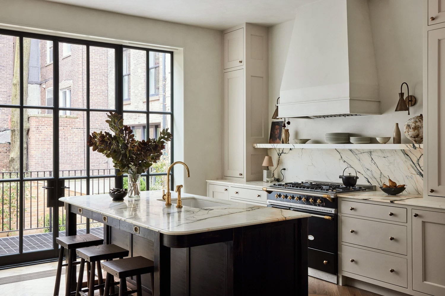 Kitchen with warm white cabinets, light wood flooring, and black range.