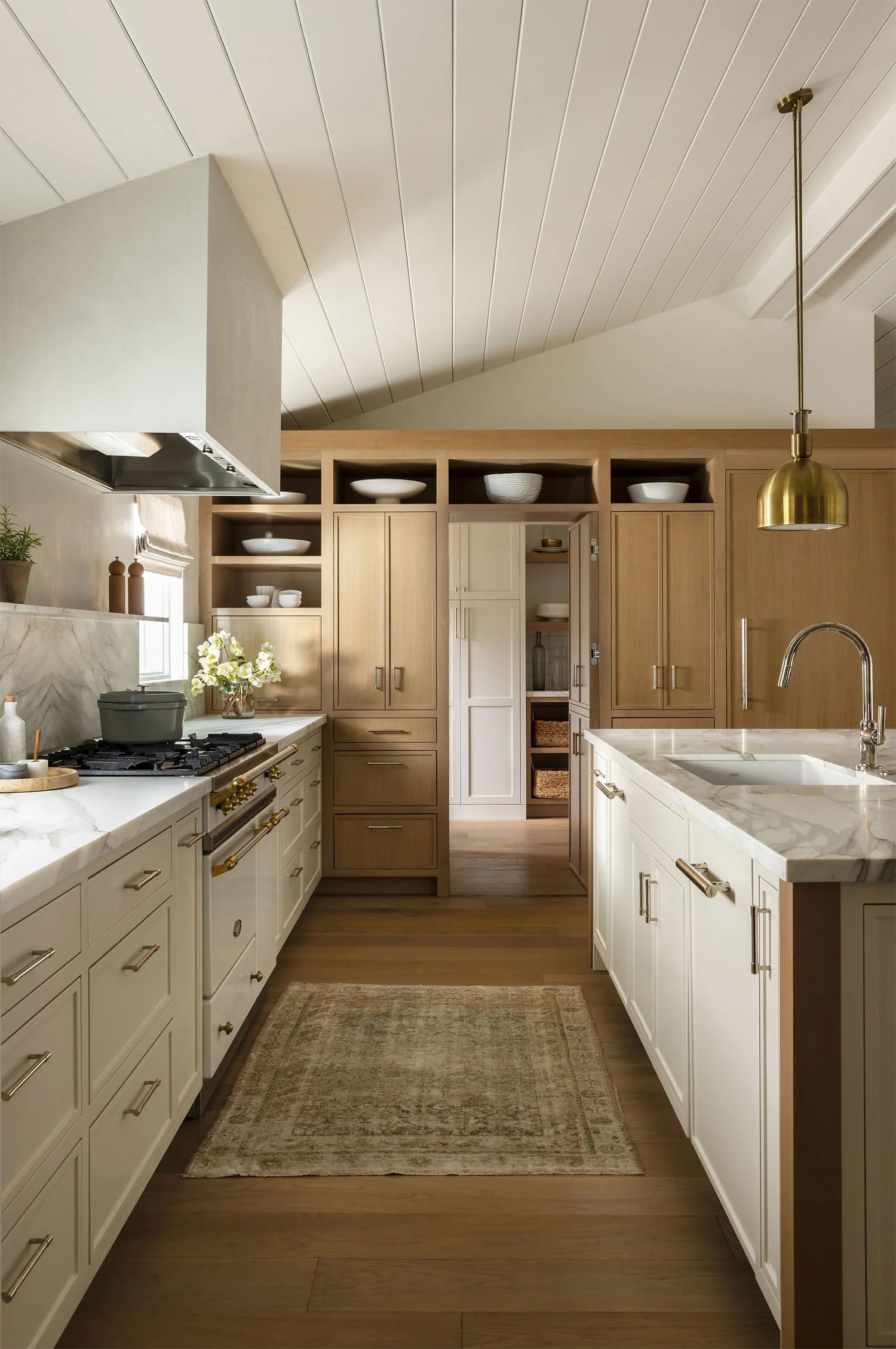 Two-tone cream and wood kitchen cabinets with light oak flooring