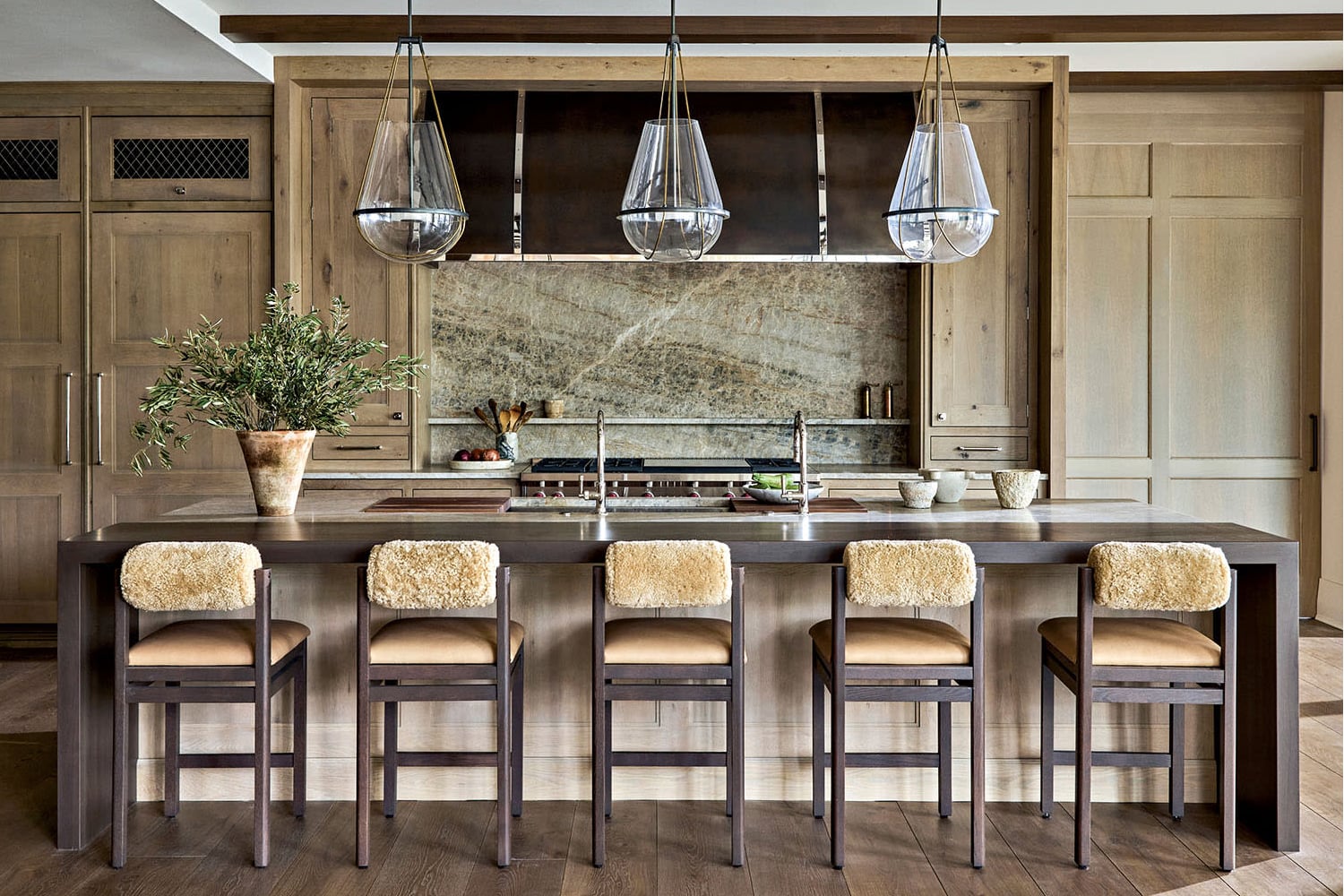 Modern farmhouse kitchen with light oak cabinets, marble backsplash and dark wood island.