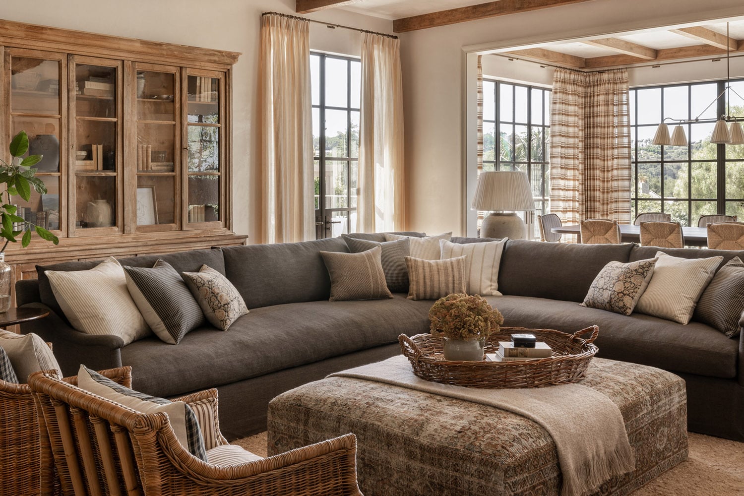 Modern farmhouse living room with a brown sectional, wicker chairs, and layered textures.