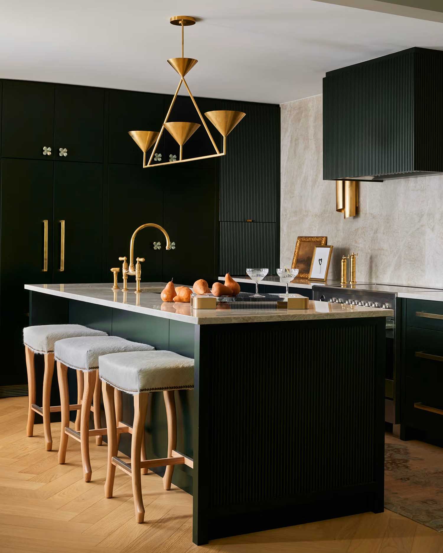 Contemporary kitchen with dark green cabinets, a reeded green range hood and gold accents.