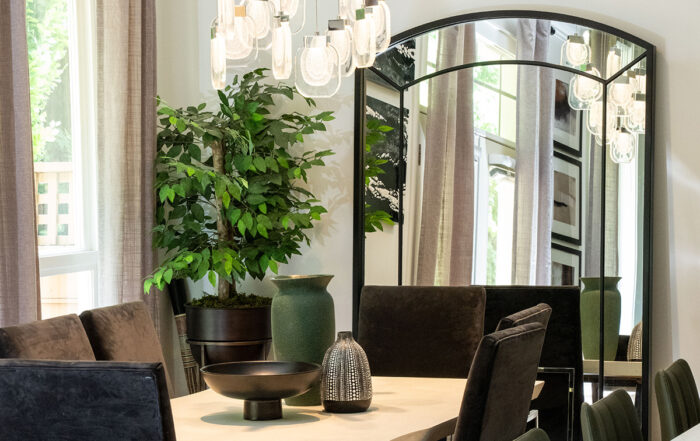 Contemporary dining room with Eurofase Paget glass pendant, charcoal velvet chairs, white raw edge table and arched mirror