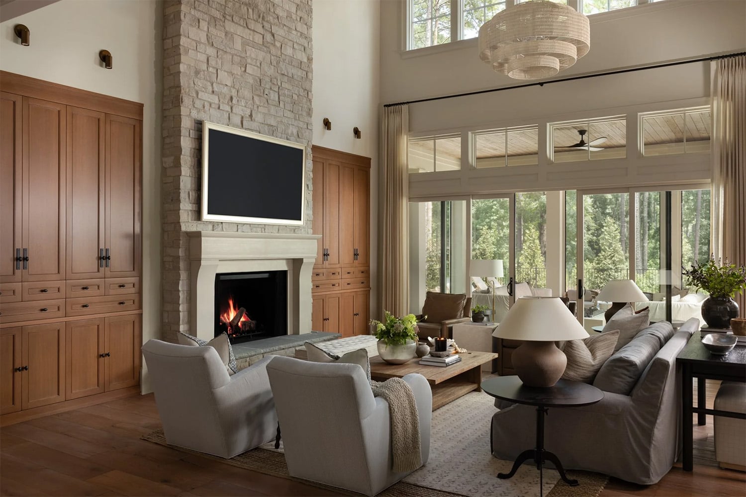 Living room with built-in wood cabinetry, a stone fireplace, and earth tone furniture paired with warm neutrals