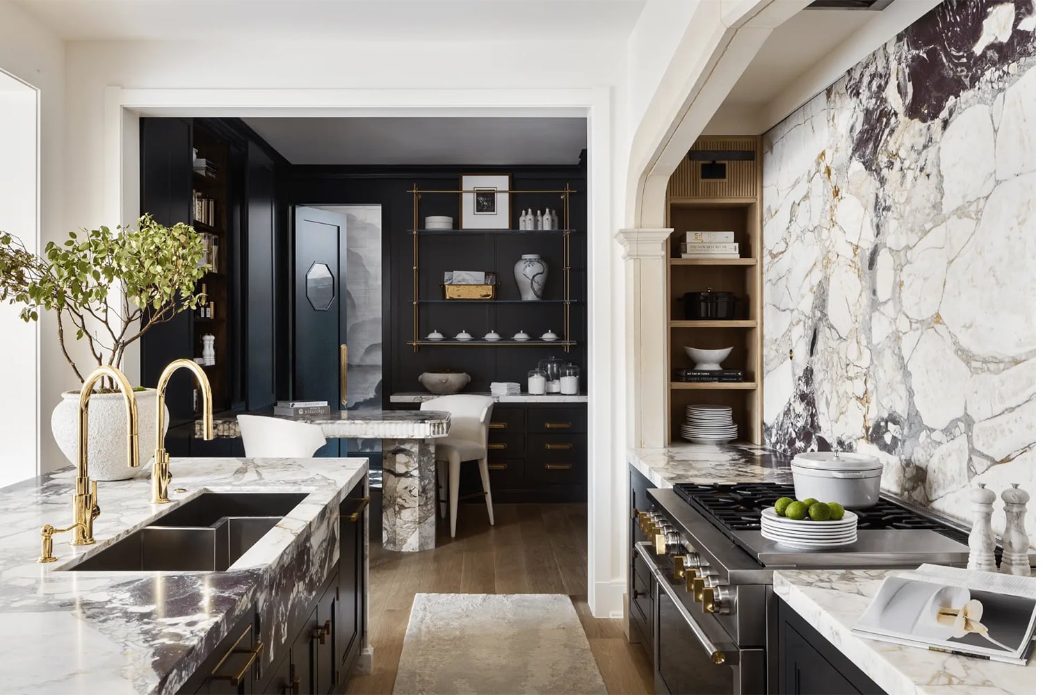 Modern luxury kitchen with black cabinetry and dramatically veined marble countertops.