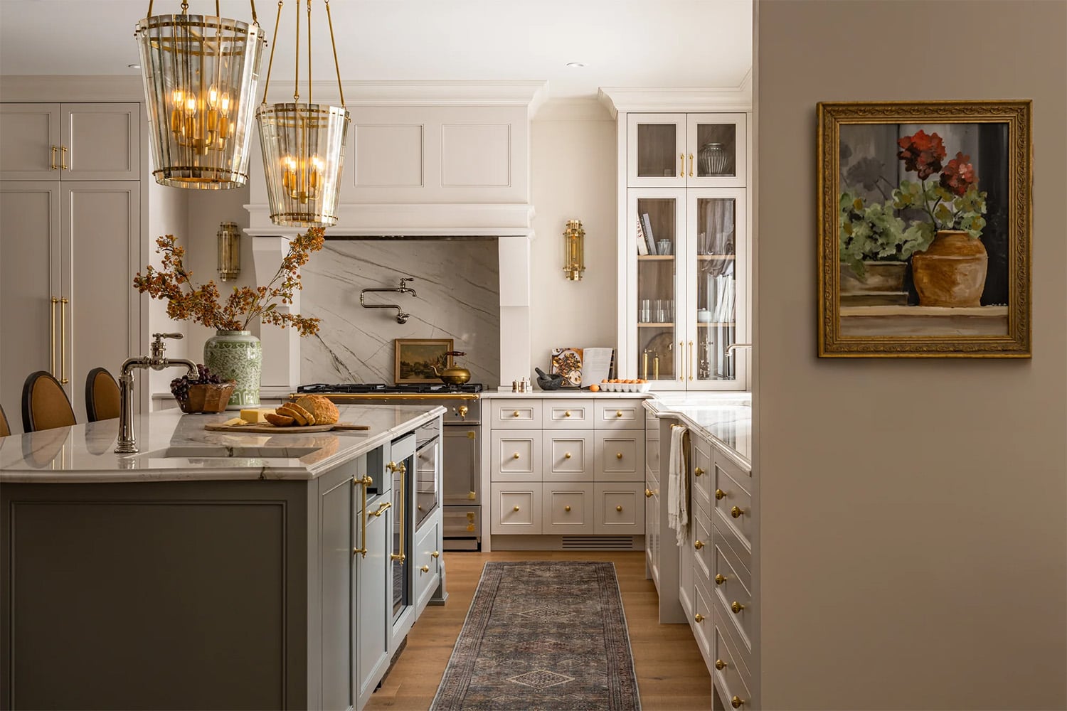 Modern farmhouse kitchen with brass pendants, a green island and cream cabinets