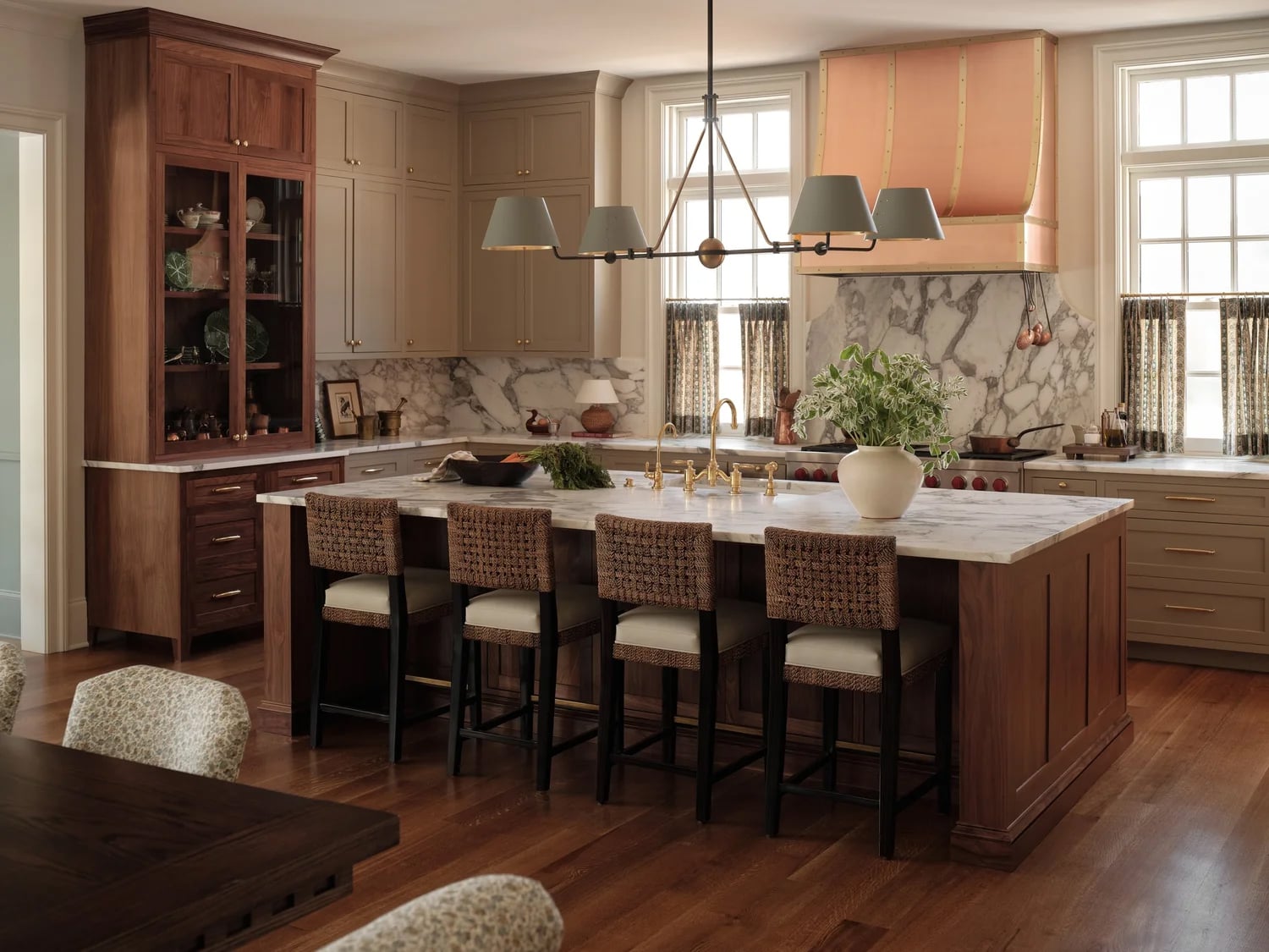 Modern farmhouse kitchen with warm wood flooring, taupe cabinets and marble countertops