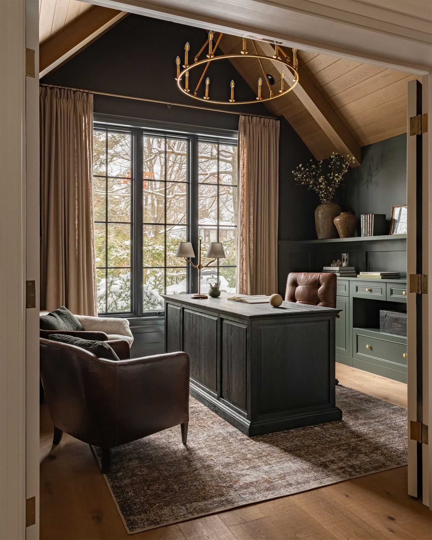 Home office with green walls and built-in cabinetry, warm wood ceilings and flooring and rich chocolate leather chairs