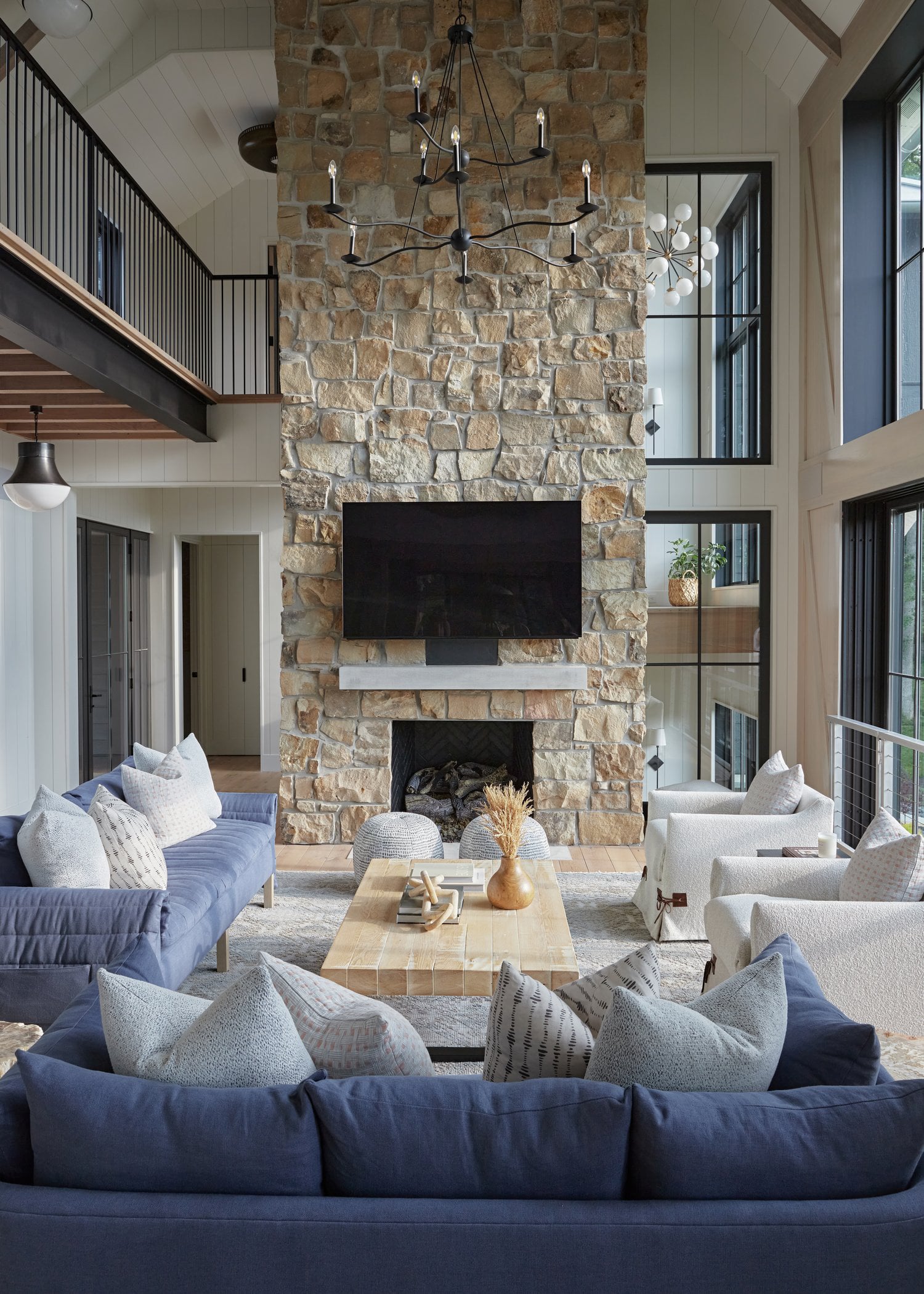 Modern coastal living room with stone fireplace, shiplap walls, and vaulted ceiling.