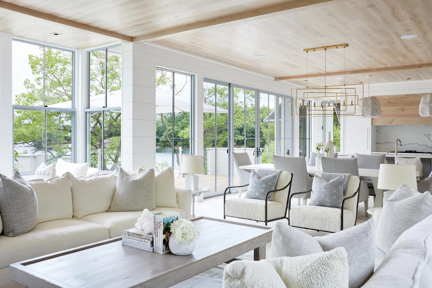 Modern coastal living room with white shiplap walls, light wood ceiling, and white furniture.
