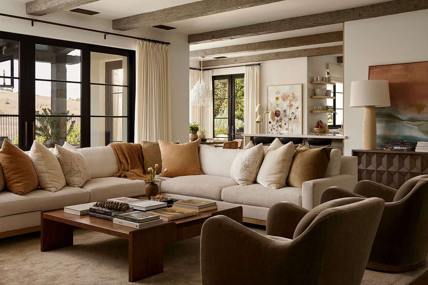 Modern rustic living room with warm white walls, rustic ceiling beams and a modern sectional in warm earth tone colors