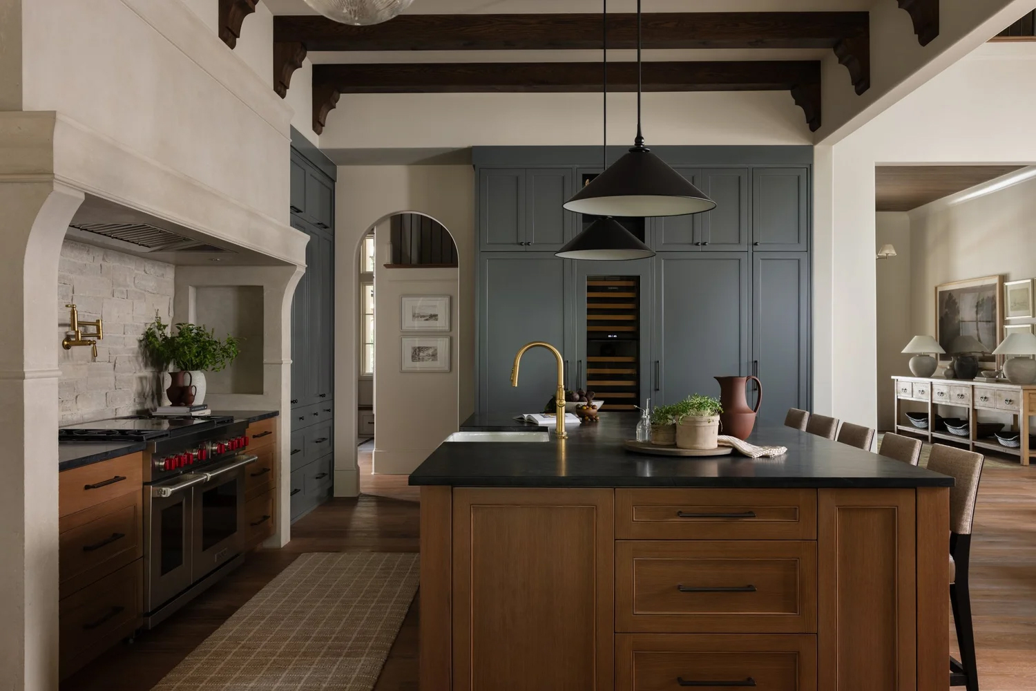 A kitchen with sage green cabinets paired with wood cabinetry and black countertops
