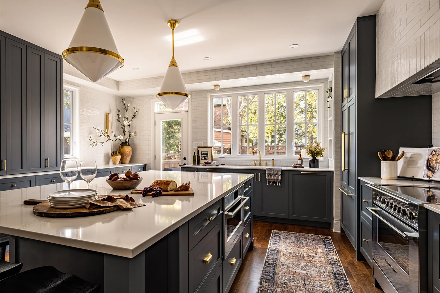 Kitchen with dark blue cabinets, white subway tile backsplash, and warm wood flooring.