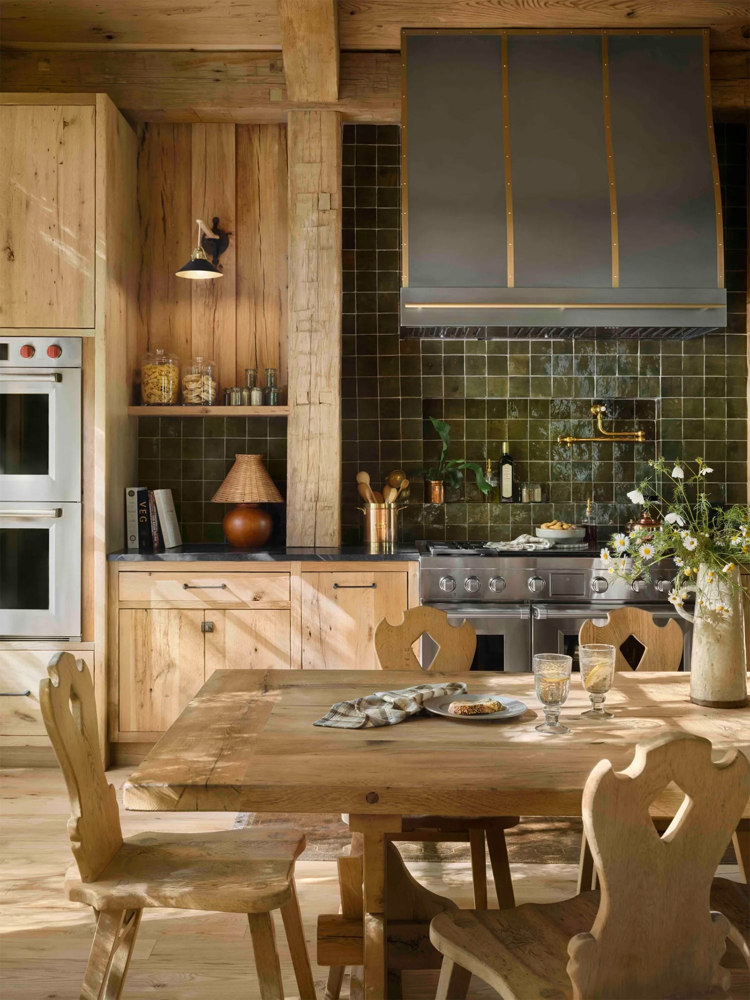 Colorado home kitchen with custom wood cabinets, large wood table, and dark green tile backsplash.