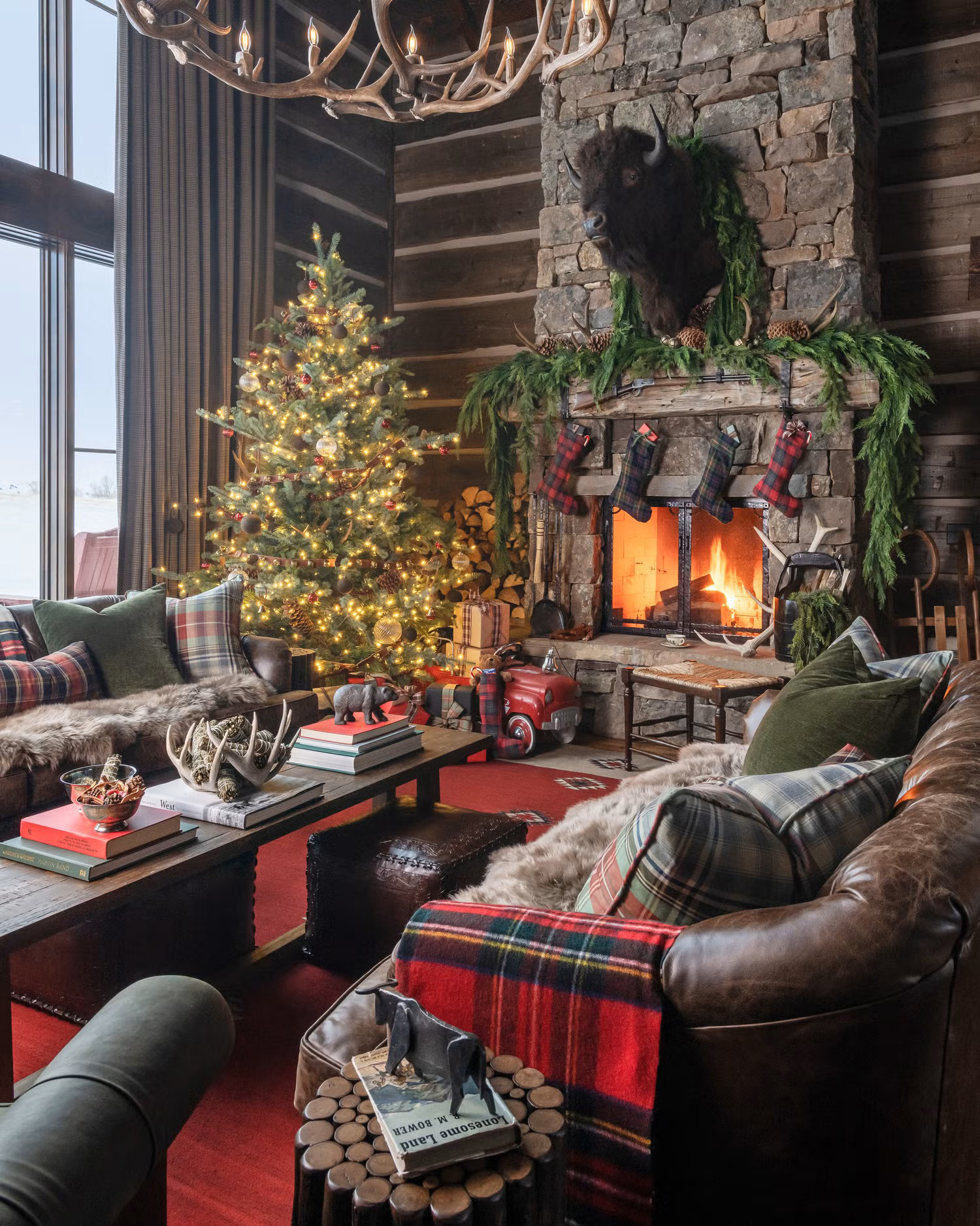 Rustic log cabin home with leather furniture, plaid blankets and pillows, and a stone fireplace